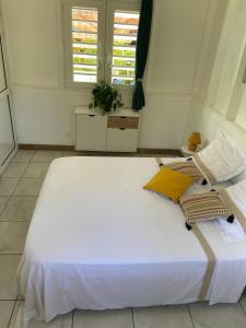 a large white bed in a room with windows at Exceptional bungalow with private pool in Rivière-Pilote
