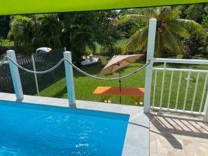 a pool with a hammock and a table and an umbrella at Exceptional bungalow with private pool in Rivière-Pilote
