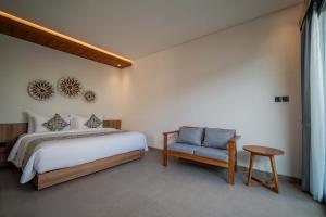 a bedroom with a bed and a chair in it at Alima Villa Ubud in Ubud