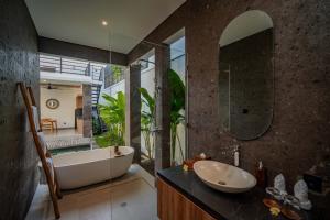 a bathroom with a tub and a sink and a mirror at Alima Villa Ubud in Ubud