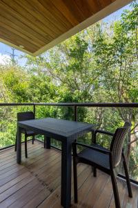 a table and chairs on a deck with trees at Jungle Loft Suite with Terrace & Natural Light - Santuario Hotel Boutique in Chemuyil