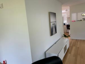 a living room with a white wall with a desk at Millingtons Beach House in Orford