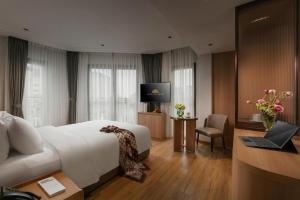 a hotel room with a bed and a desk with a laptop at Hong Ngoc Cochinchine Boutique Hotel & Spa in Hanoi