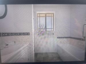 a white bathroom with a shower and a window at Millingtons Beach House in Orford +22 photos