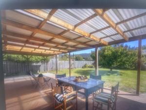 a patio with a table and chairs under a pergola at Millingtons Beach House in Orford
