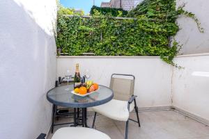 a table with a bowl of fruit and a bottle of wine at Apartments Niko in Cavtat