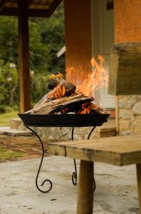 a grill with a fire in it next to a bench at Pousada do Nonno in Venda Nova do Imigrante