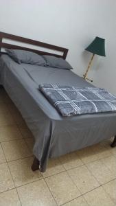 a bed with a blue comforter and a lamp at Hostal Travesía Urbana in Guadalupe