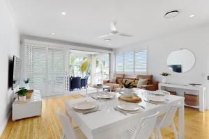 a white dining room with a white table and chairs at 19 Colonial in Noosaville