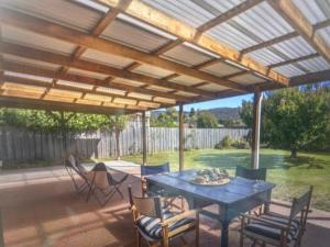 a patio with a wooden pergola with a table and chairs at Millingtons Beach House in Orford
