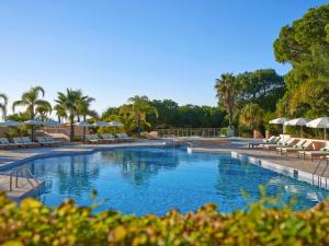 a large swimming pool with chairs and umbrellas at Hotel Quinta do Lago in Quinta do Lago