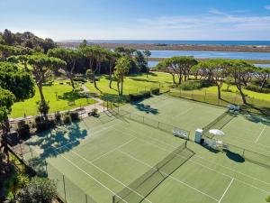 a grassy area with a tennis court and trees at Hotel Quinta do Lago in Quinta do Lago