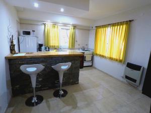 uma cozinha com um balcão e dois bancos em Cabañas Victoria em Mar de las Pampas