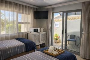 a hotel room with two beds and a balcony at OceanBreeze50 Stylish Garden Route Stay in Central Mossel Bay in Mossel Bay
