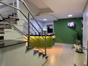a lobby with stairs and a green wall at Hotel 44 Oliveira in Goiânia