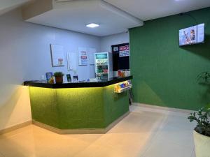 a shop with a green wall and a counter at Hotel 44 Oliveira in Goiânia +29 photos