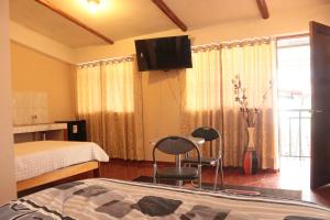 a bedroom with a bed and two chairs and a tv at Lechugal Guest House in Cusco