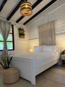 a bedroom with a white bed and a chandelier at Cardedeu Residence Cangrejera in La Libertad