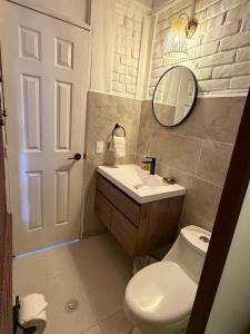 a bathroom with a toilet and a sink and a mirror at Cardedeu Residence Cangrejera in La Libertad