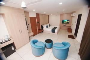 a hotel room with two blue chairs and a bed at Empire Suites in Erāttupetta