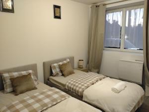 two beds in a small room with a window at Ô Bon Goût in Bourges