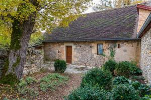 une maison en pierre avec un arbre en face de celle-ci dans l'établissement Clos Sandrine Gindou Lot, à Gindou