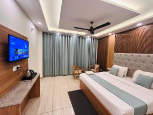 a bedroom with a large bed and a flat screen tv at Oakleaf Hotel & Resort - A Classic Rooms & Prime Location Near Library Chowk in Mussoorie