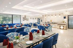 a dining room with tables and blue chairs and a kitchen at OPO Horizon LYRO Hotel , Formerly known as Inde Hotel in Gurgaon
