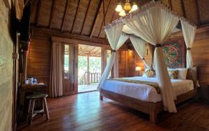 a bedroom with a canopy bed with a window at Sirya Farm House in Meliling
