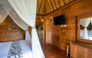 a bedroom with a canopy bed and a tv at Sirya Farm House in Meliling