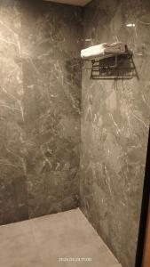 a bathroom with a stone wall with a towel at Hotel Shubham Prestige in Surūrnagar