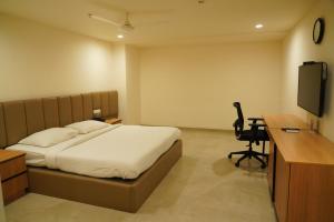 a bedroom with a bed and a desk and a computer at Hotel Shubham Prestige in Surūrnagar