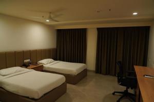 a hotel room with two beds and a desk at Hotel Shubham Prestige in Surūrnagar