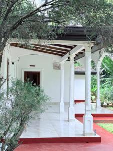 a pavilion with white columns in a garden at Niwasa Habarana in Habarana +10 photos