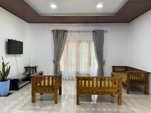a living room with three wooden chairs and a window at Niwasa Habarana in Habarana