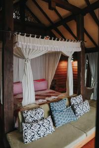 a bedroom with a canopy bed with pillows at Baan Mon Muan in Mon Jam
