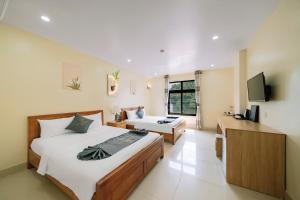 a hotel room with two beds and a television at Cat Ba Flora Hotel in Cat Ba