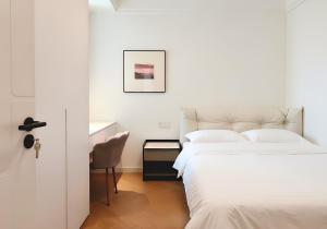 a white bedroom with two beds and a chair at Merit黄浦 Bright and Modern 2Bed Condo unit in downtown Shanghai in Shanghai