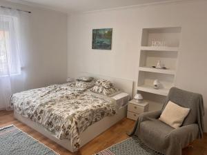 a bedroom with a bed and a chair at Ladislaus Garden Suites in Cegléd