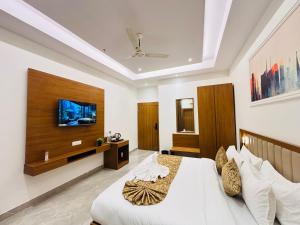 a bedroom with a bed and a tv on the wall at Arth Suites Lucknow Gomti Nagar in Lucknow