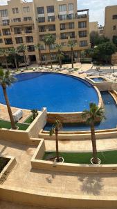 a large pool with palm trees in front of a building at Samarah E 01 full Sea View and adult pool prime location with garden , in Al Baḩḩāth