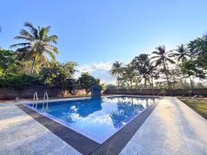 a swimming pool with palm trees in the background at Singha Holiday Bungalow in Ibbagomuwa