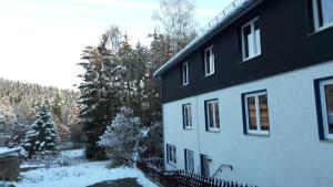 una casa bianca e nera con la neve sopra di Haus Steeg a Braunlage