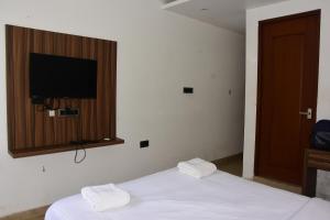 a bedroom with two beds and a flat screen tv at Bihotels And Resorts in Yercaud