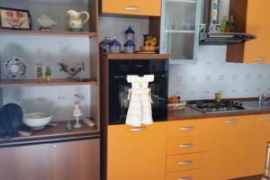 クストナーチにあるCornino Relaxのキッチン(オレンジ色のキャビネット、コンロ、エプロン付)