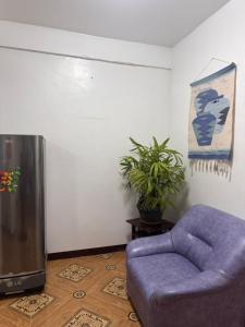 a living room with a purple couch and a tv at Mabel's Garden Stay in Puerto Galera