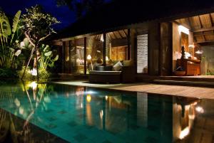 a swimming pool in front of a house at night at Komea Villa in Canggu