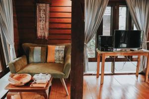a living room with a chair and a table with a tv at Baan Mon Muan in Mon Jam