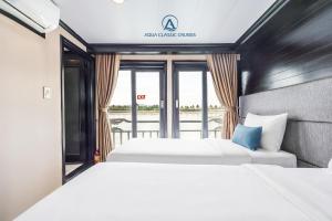 two beds in a hotel room with a window at Aqua Classic Cruise in Ha Long