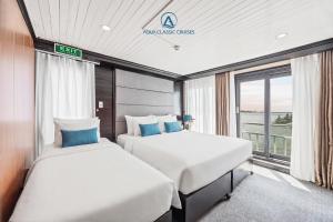 two beds in a room with a window at Aqua Classic Cruise in Ha Long +87 photos